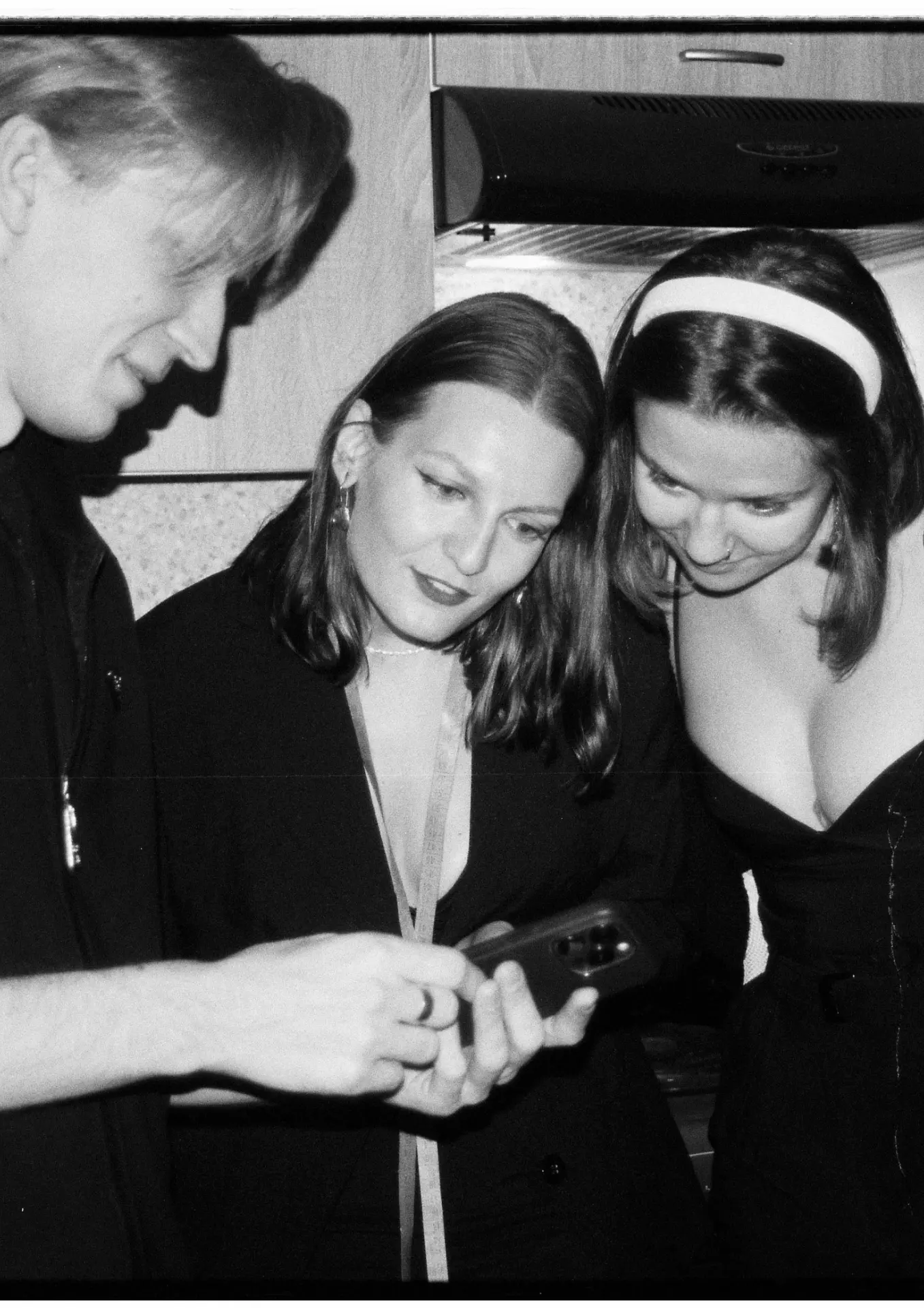 Three friends looking at a phone together, planning a night out